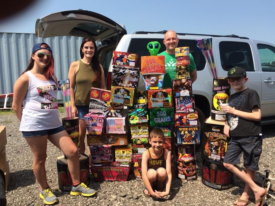 A group of people are standing in front of a van filled with fireworks.