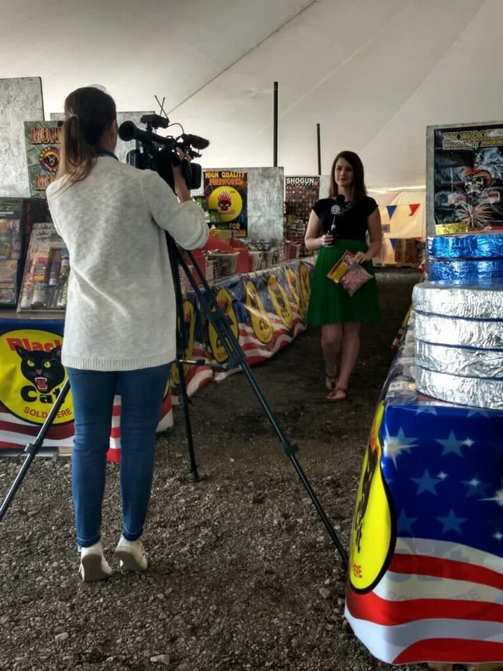 A woman is talking into a microphone while a cameraman takes a picture