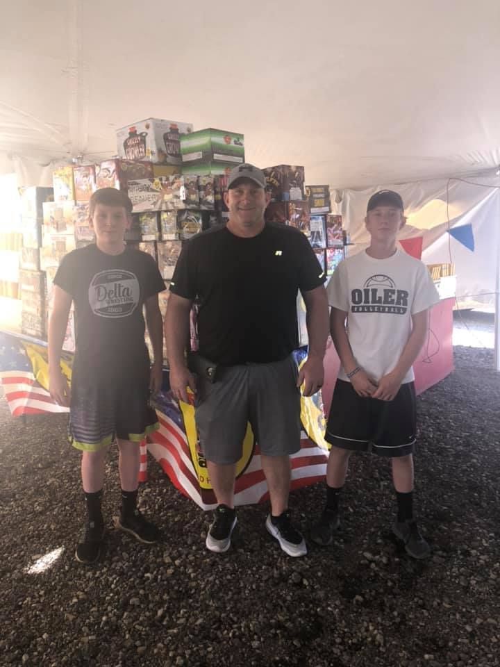 A man and two boys are standing in front of an american flag.