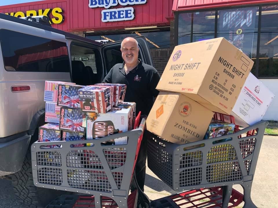 A man is loading fireworks into a shopping cart.
