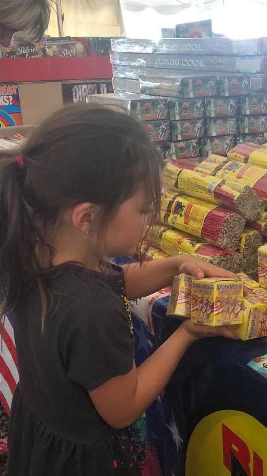 A little girl is holding a box of crackers in a store.