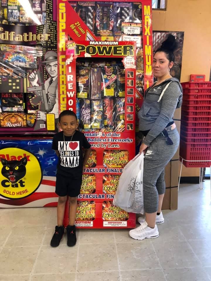 A woman and a child are standing in front of a display of fireworks.