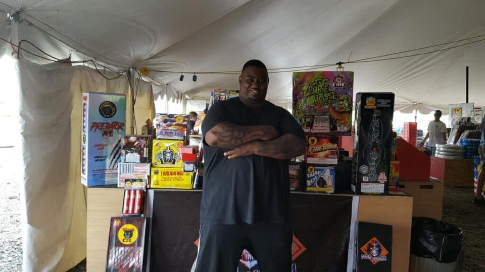 A man standing in front of a table with a sign that says ' coca cola ' on it