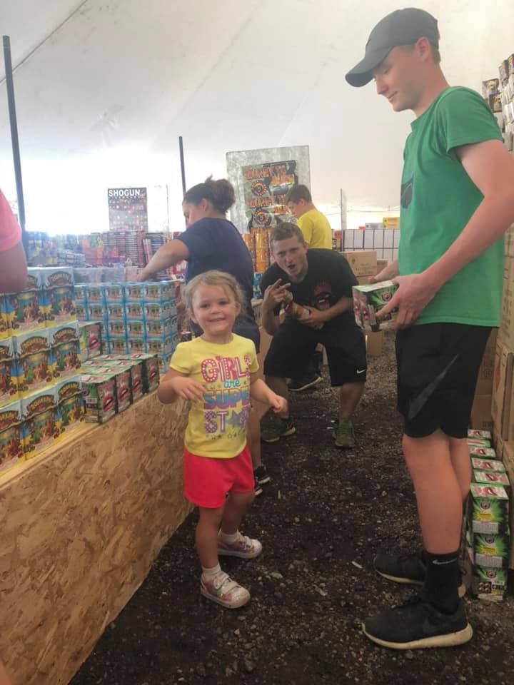 A little girl in a yellow shirt is standing next to a man in a green shirt.