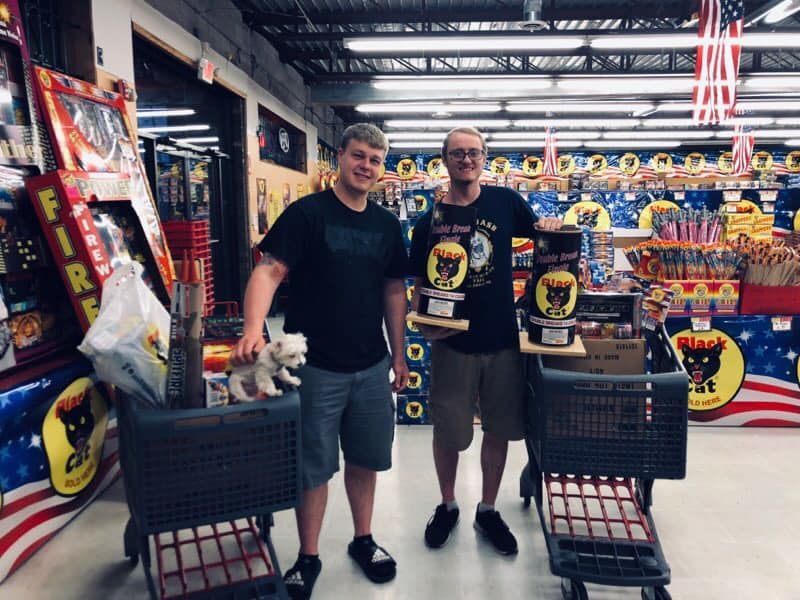 Two men standing next to each other in a store with a dog in a shopping cart