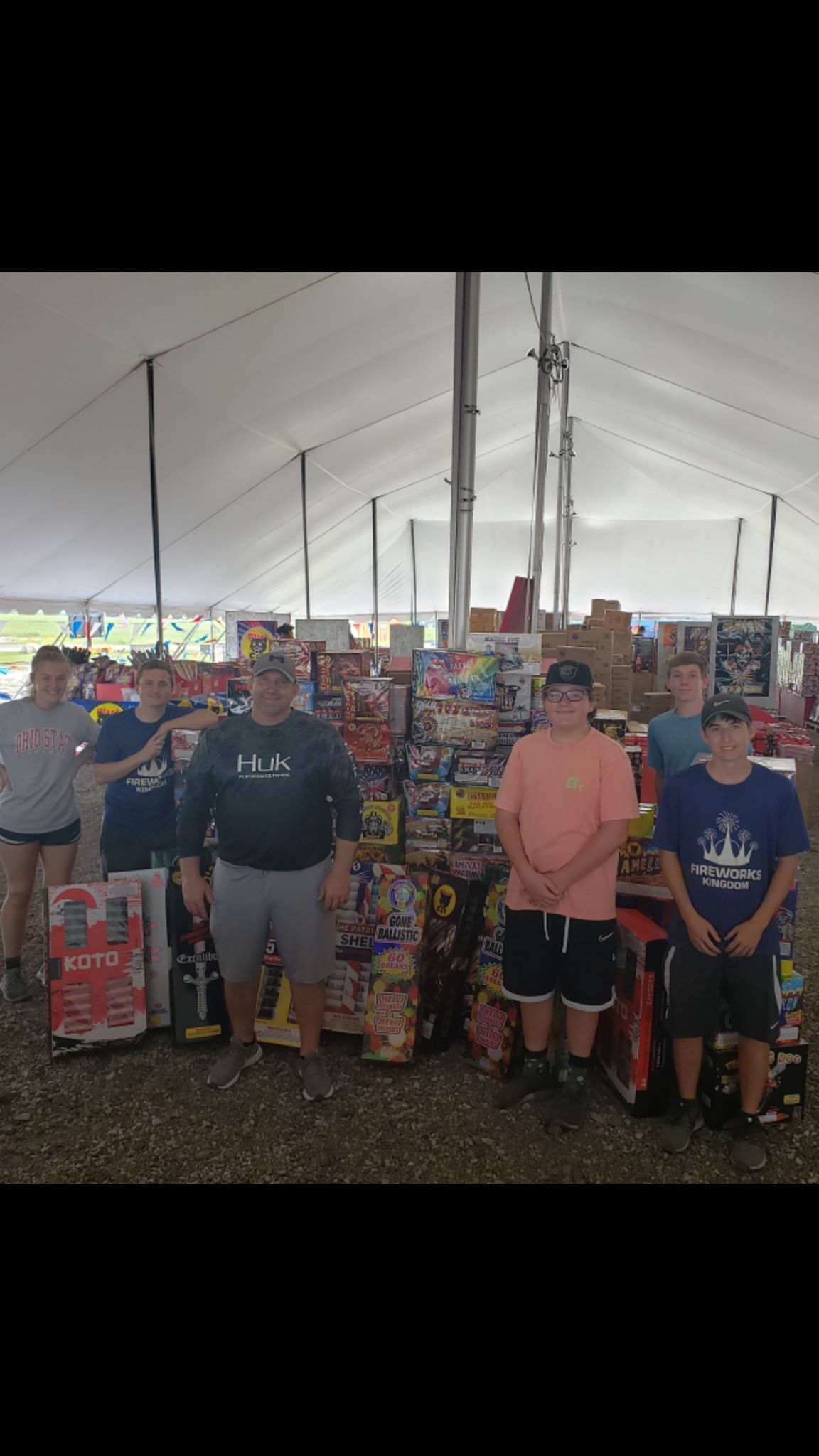 A group of men are standing in front of a large tent filled with lots of toys.