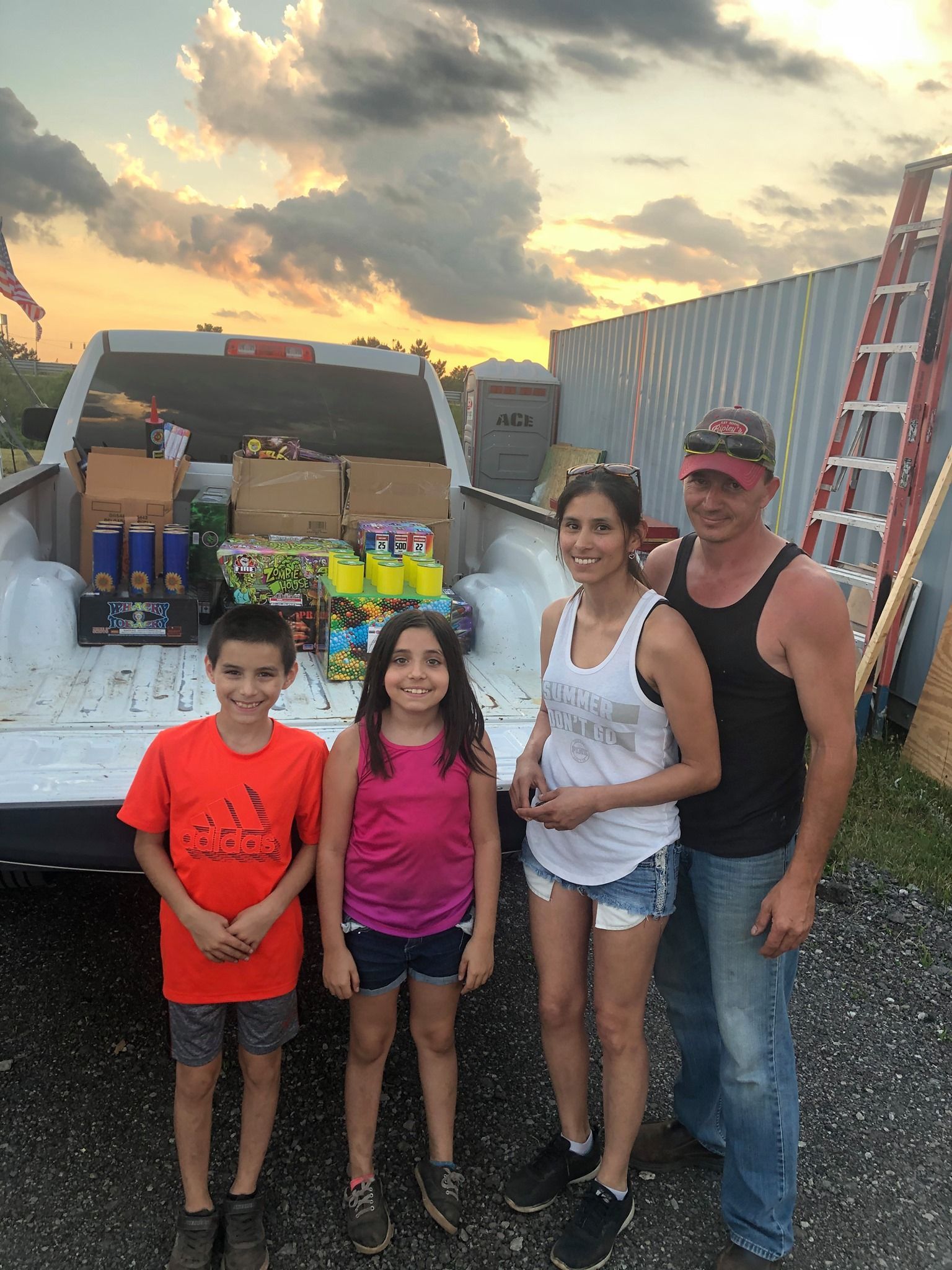 A family is standing in front of a truck filled with food.