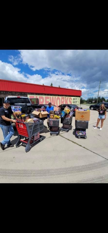 A group of people are pushing shopping carts full of food in a parking lot.