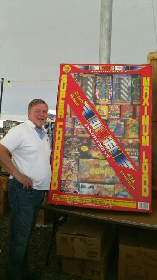 A man is standing next to a large box of fireworks.