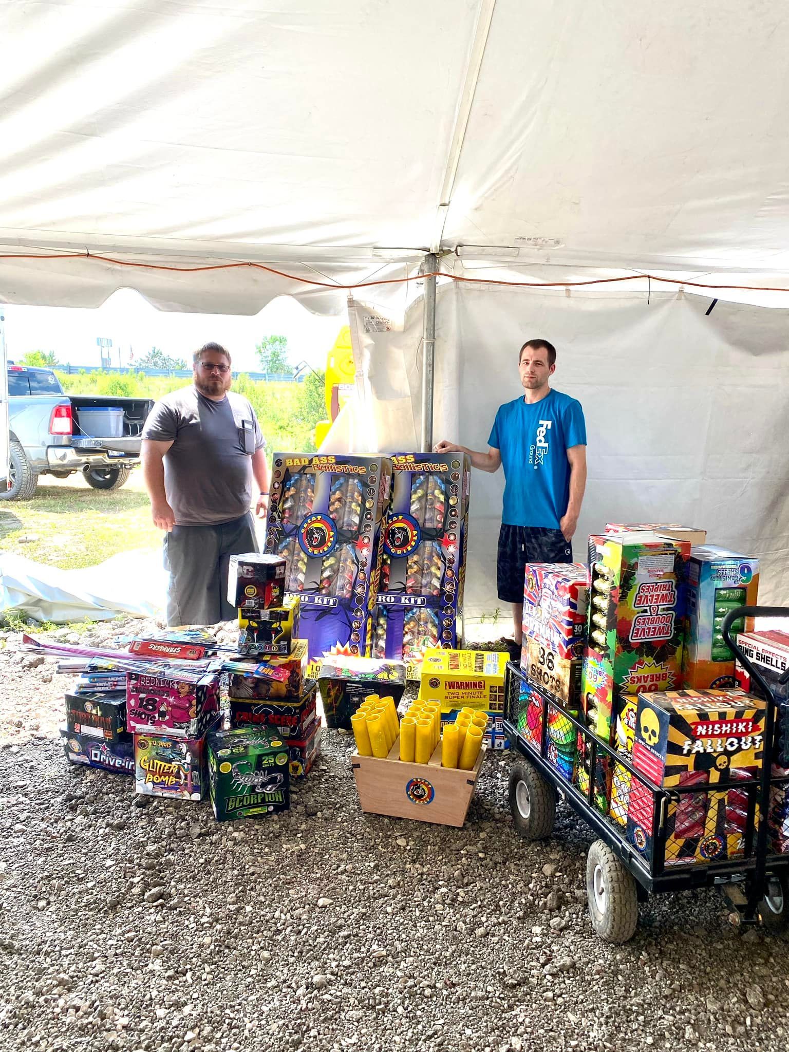 Two men are standing in front of a tent filled with fireworks.