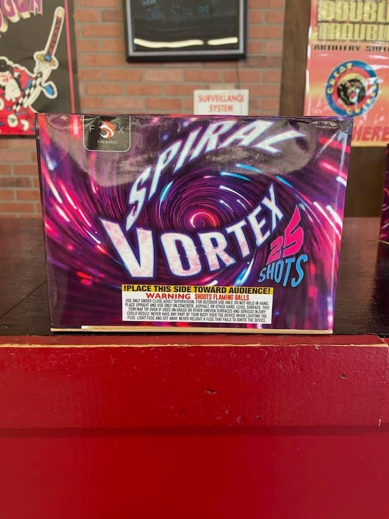 A box of spiral vortex fireworks is sitting on a red table.