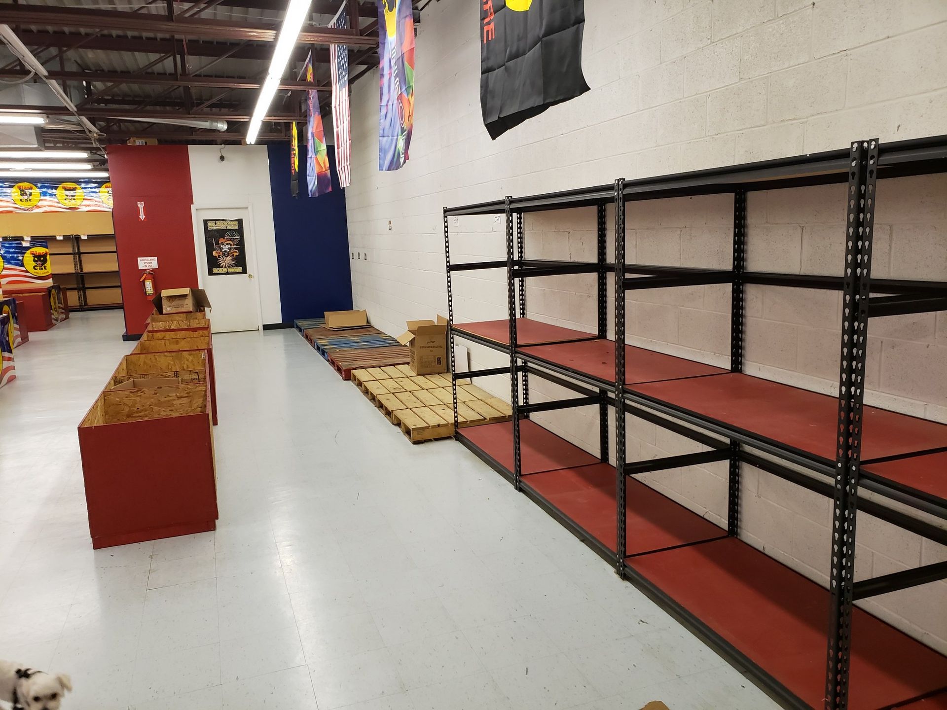 A warehouse with empty shelves and pallets on the floor