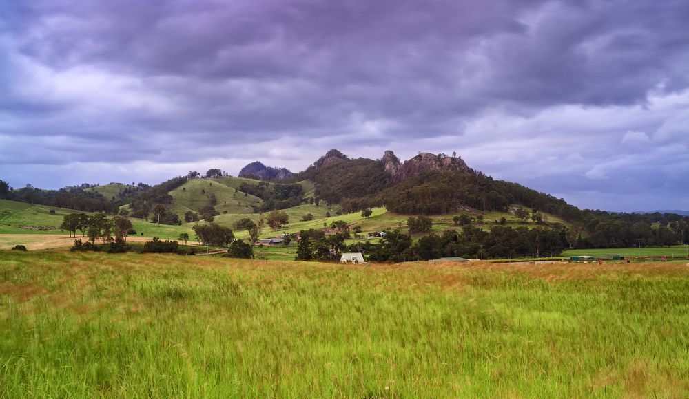 A Field With A Mountain In The Background And A Cloudy Sky — AMW Contracting Co In Cobraball, QLD