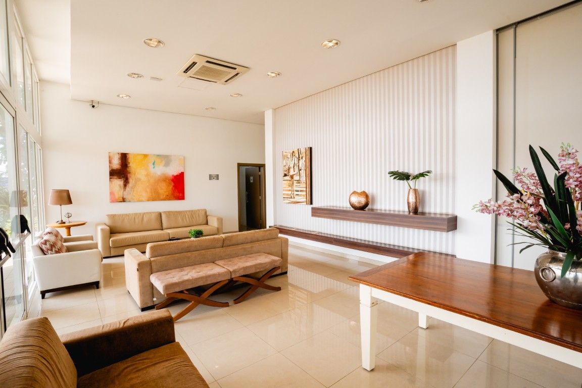 Uma sala de estar com um sofá, cadeira, mesa e vaso de flores.