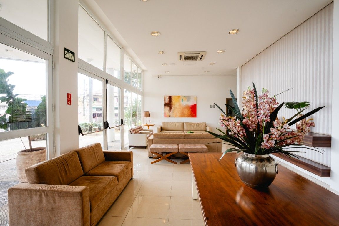 Uma sala de estar com um sofá, mesa e vaso de flores.