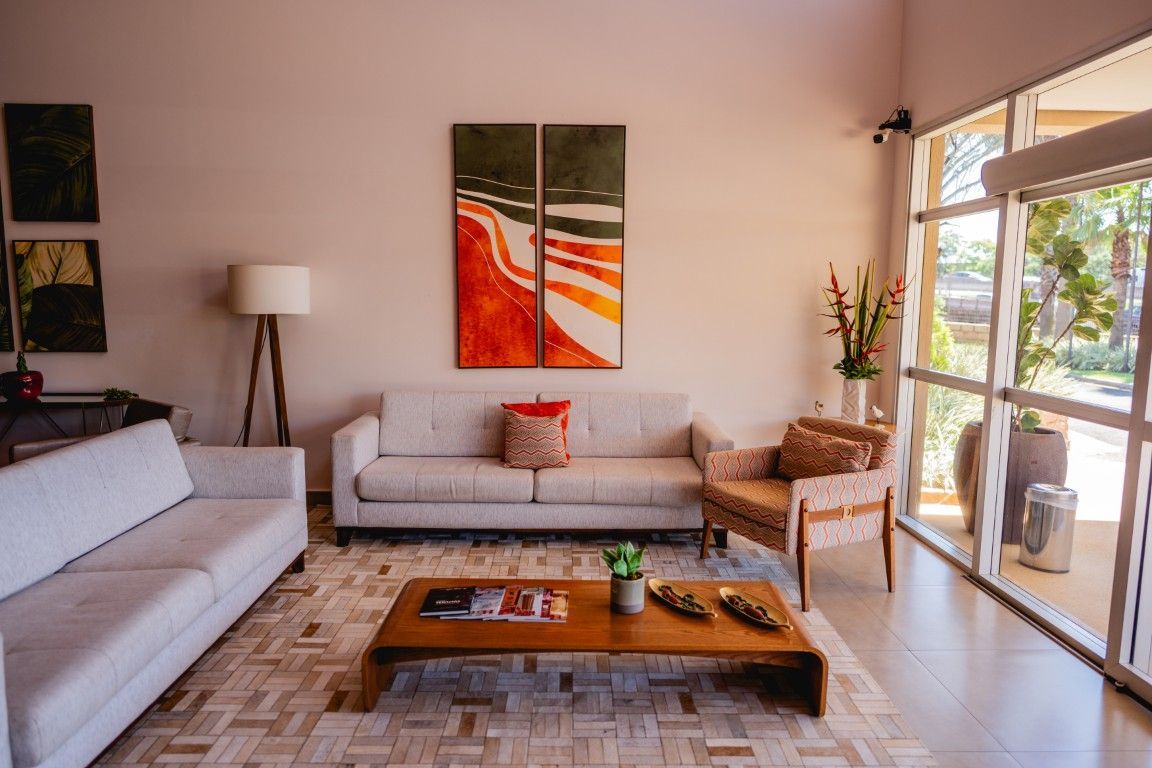 Uma sala de estar com um sofá, cadeira, mesa de centro e pinturas na parede.