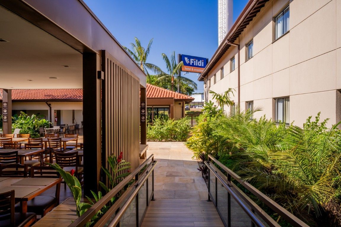 Uma passarela de madeira que leva a um hotel com mesas e cadeiras.