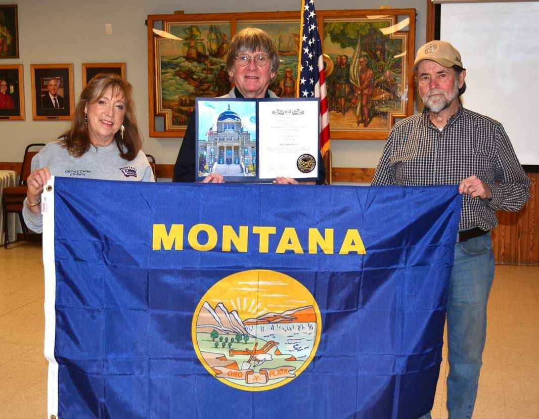 Three people holding a montana flag and a certificate