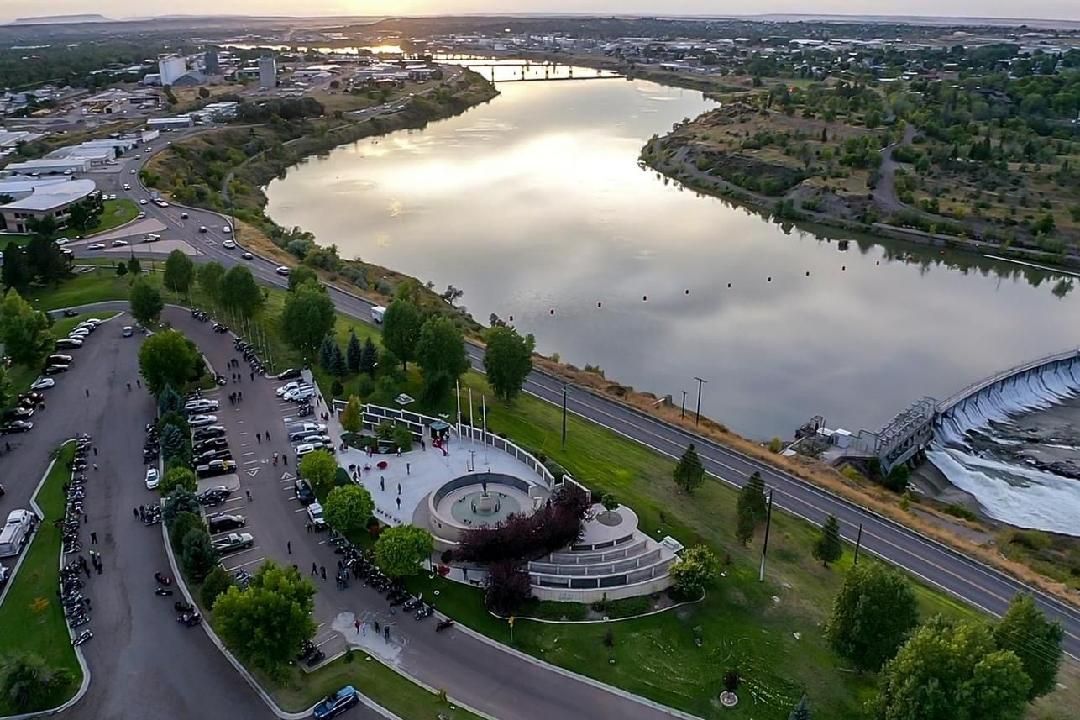 An aerial view of a lake surrounded by trees and a road.