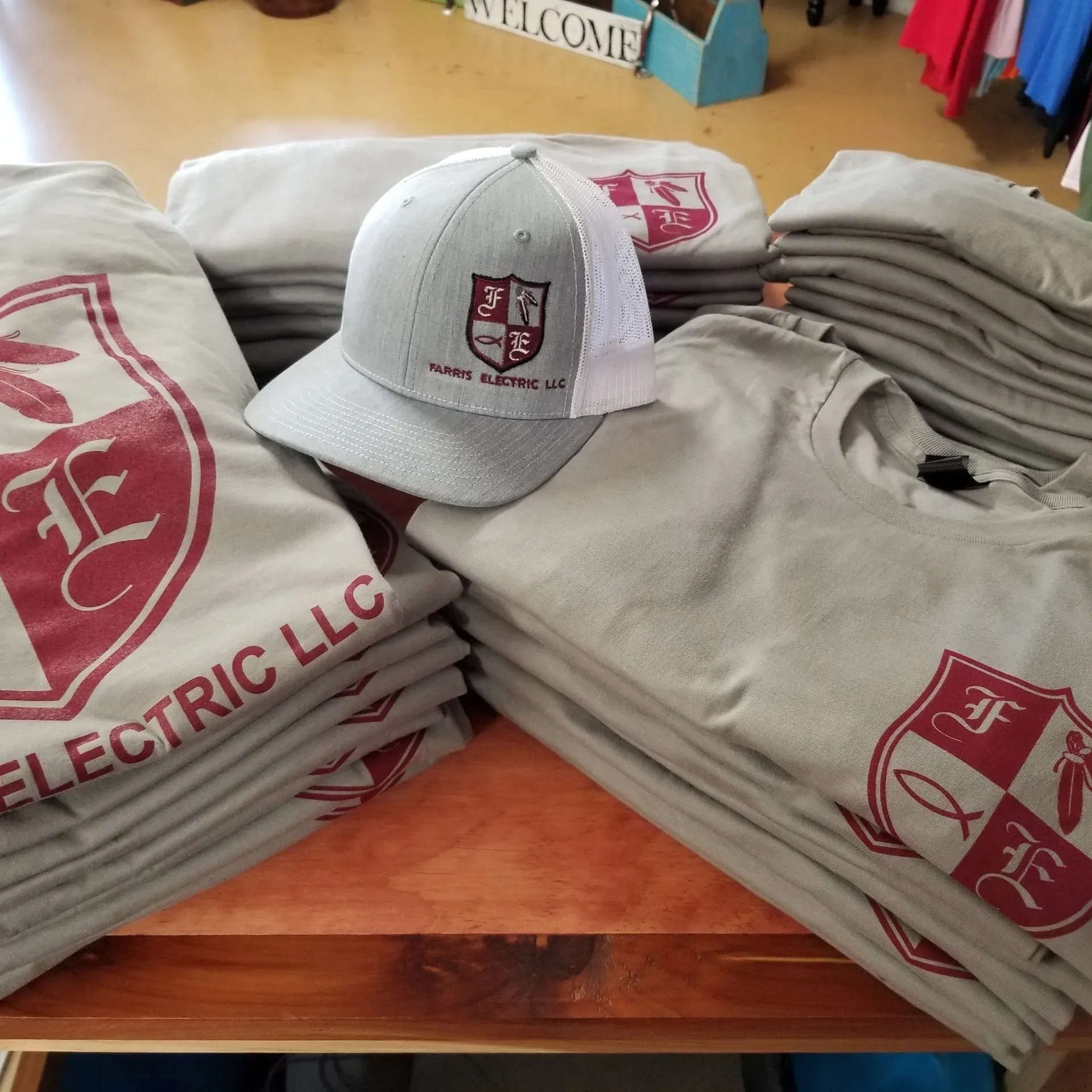 Stacks of gray t-shirts and a hat with a logo that reads