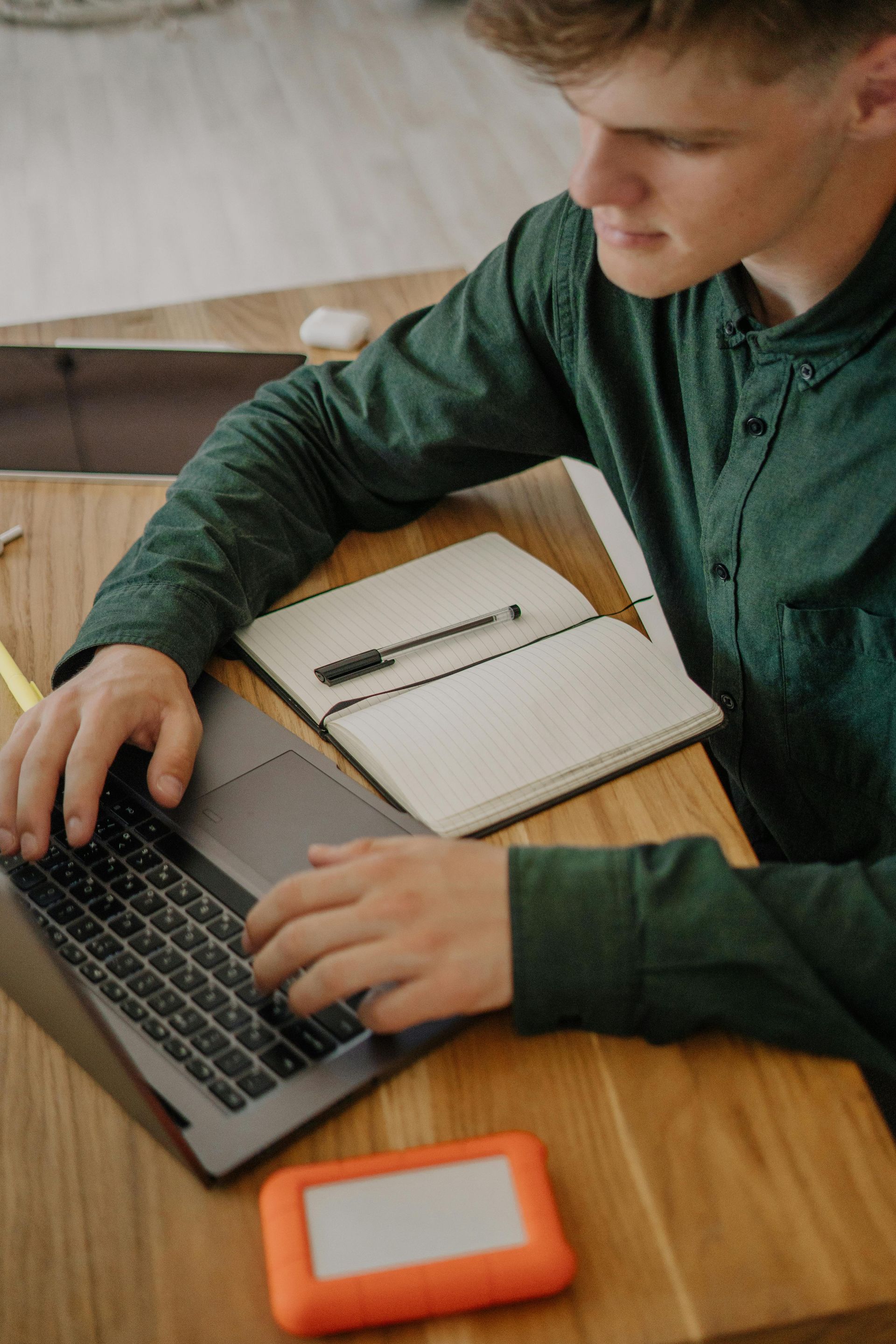 A young man is sitting at a table using a laptop computer.