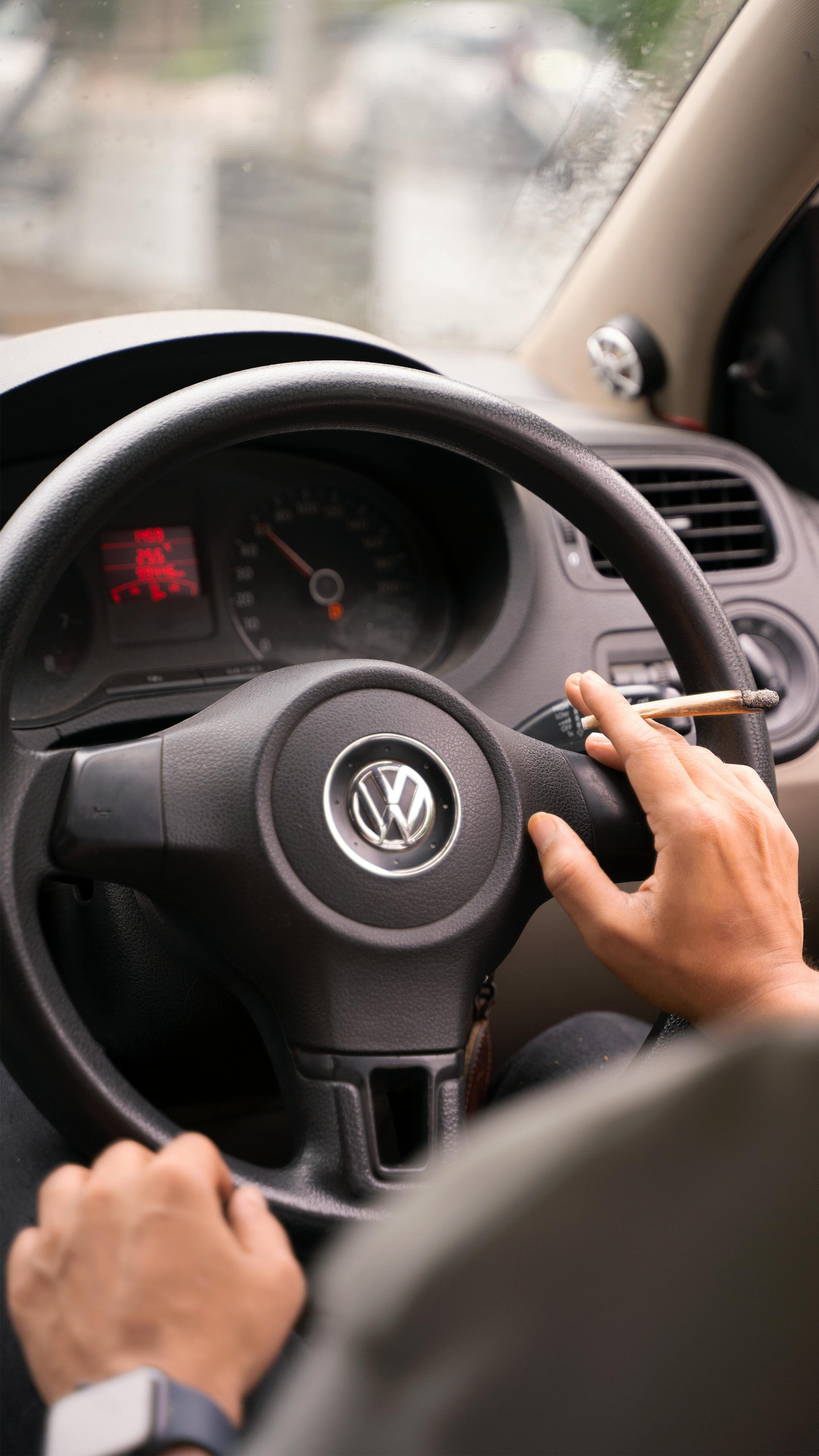 Hands on a Volkswagen steering wheel while driving, with a dashboard and road visible ahead