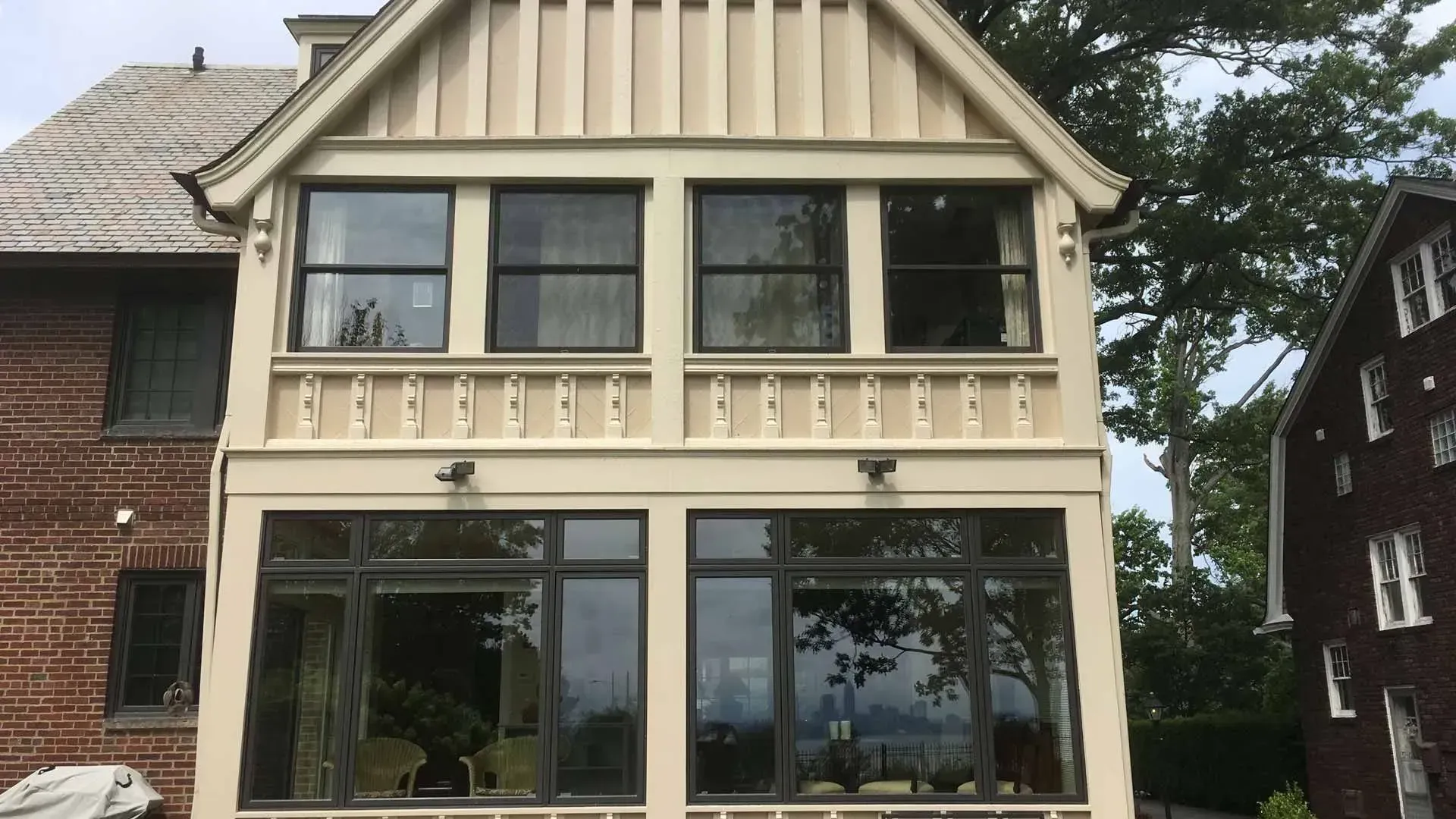 Cream-colored two-story house facade with large front windows and striped gable trim