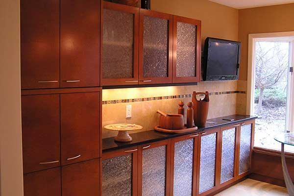 Built-in kitchen cabinets with wood finish, countertop appliances, and a small TV by a bright window