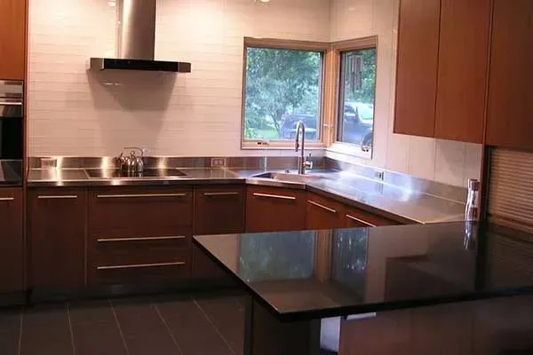 Modern kitchen with dark cabinets, black countertop island, stainless steel appliances, and window over sink