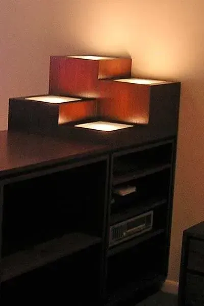 Stacked illuminated wooden shelf on a dark cabinet in a warm-lit room