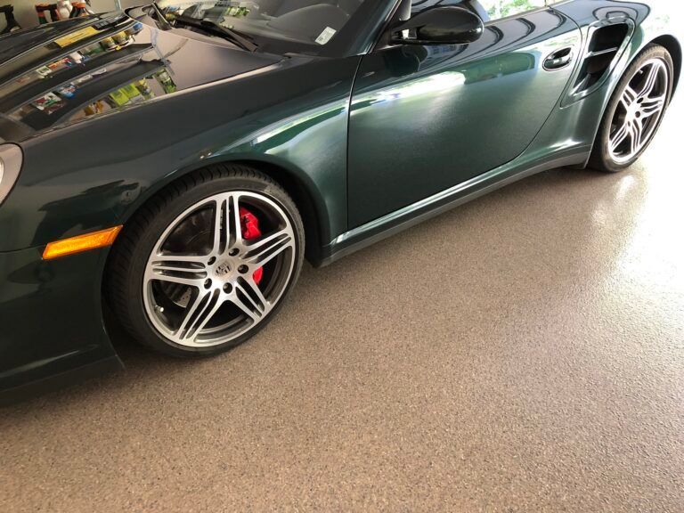 A green porsche 911 turbo is parked in a garage.