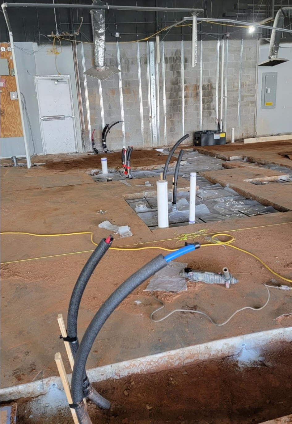 Person installing gray PVC pipes in a trench.