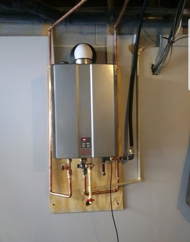 Plumber fixing a water heater on a white wall; uses a wrench and wears gloves. Plumber fixing a water heater on a white wall; uses a wrench and wears gloves.