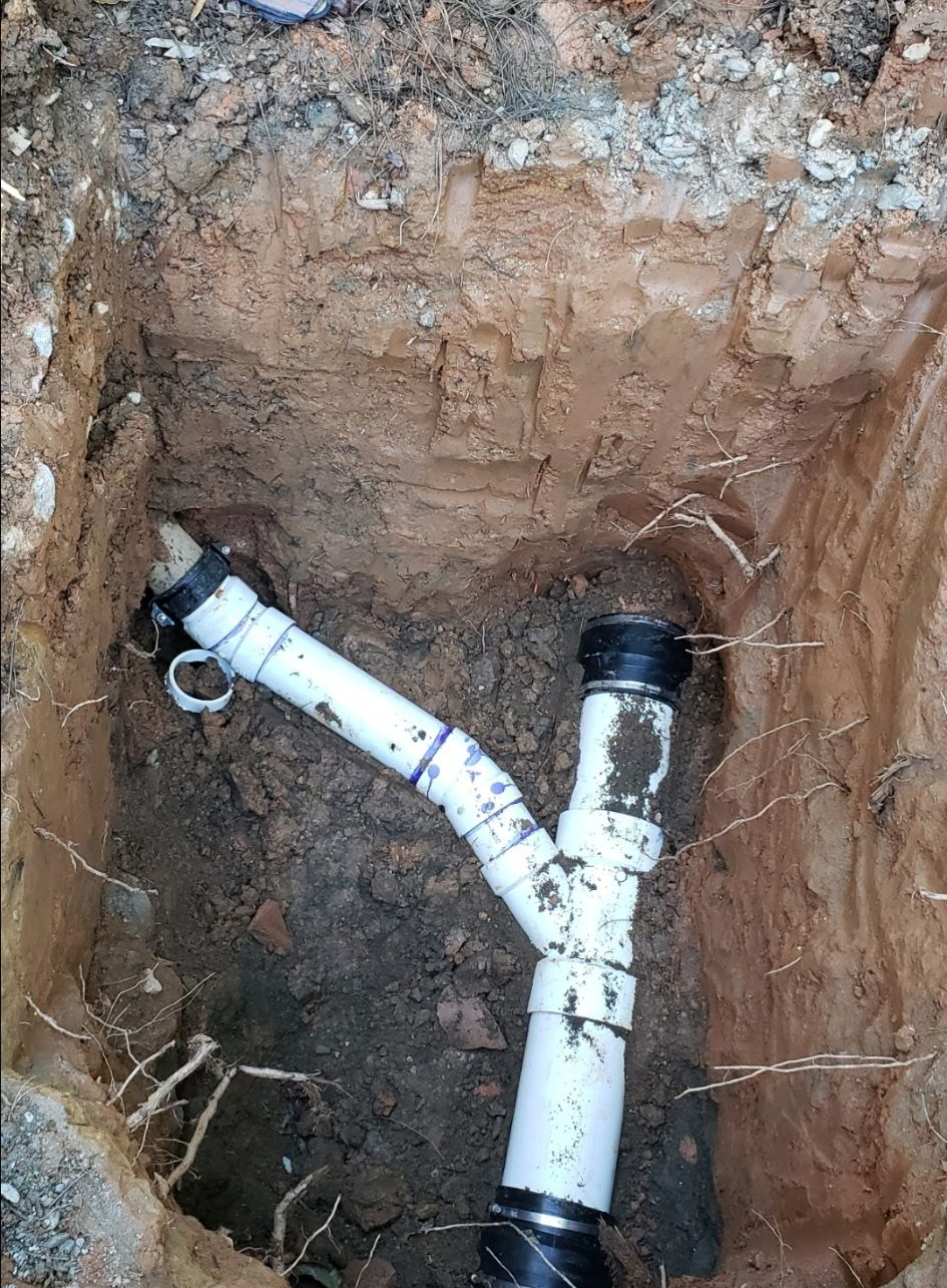 Plumber using a wrench to work on the pipes under a white sink. Plumber using a wrench to work on the pipes under a white sink.