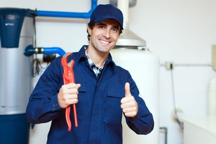 Plumber working under a kitchen sink, tools beside him on the floor.