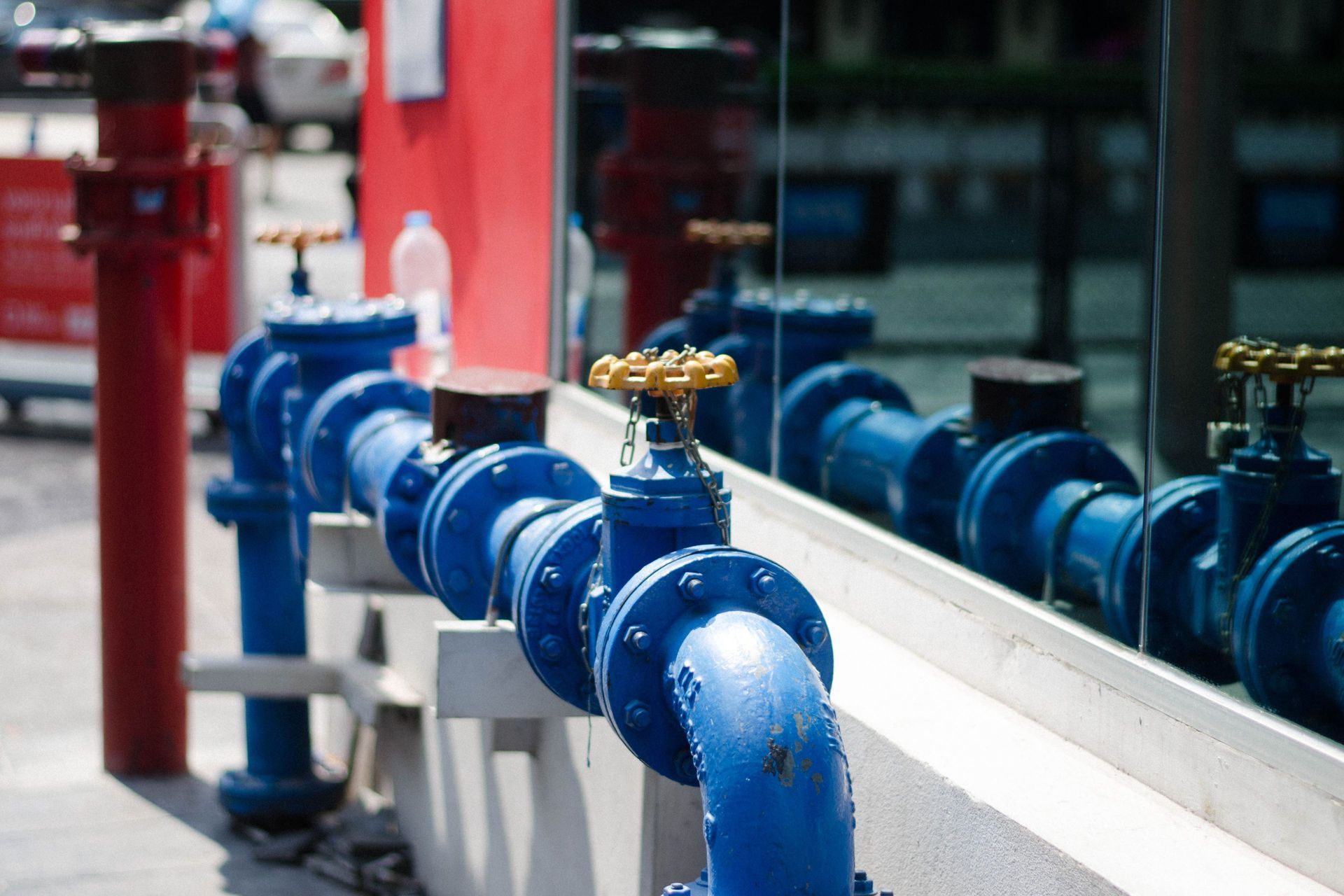 Blue water pipes with gold valves reflected in a window. Blue water pipes with gold valves reflected in a window.