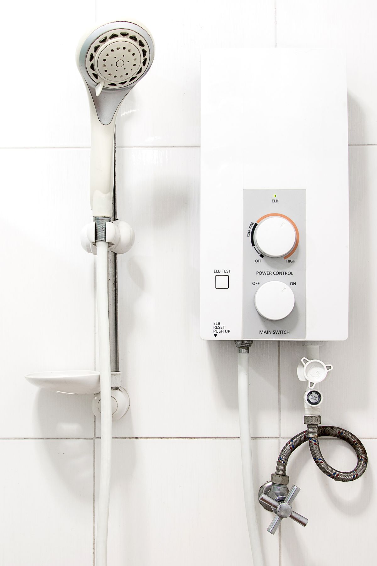 White, cylindrical water heater mounted on a tiled wall in a corner. White, cylindrical water heater mounted on a tiled wall in a corner.