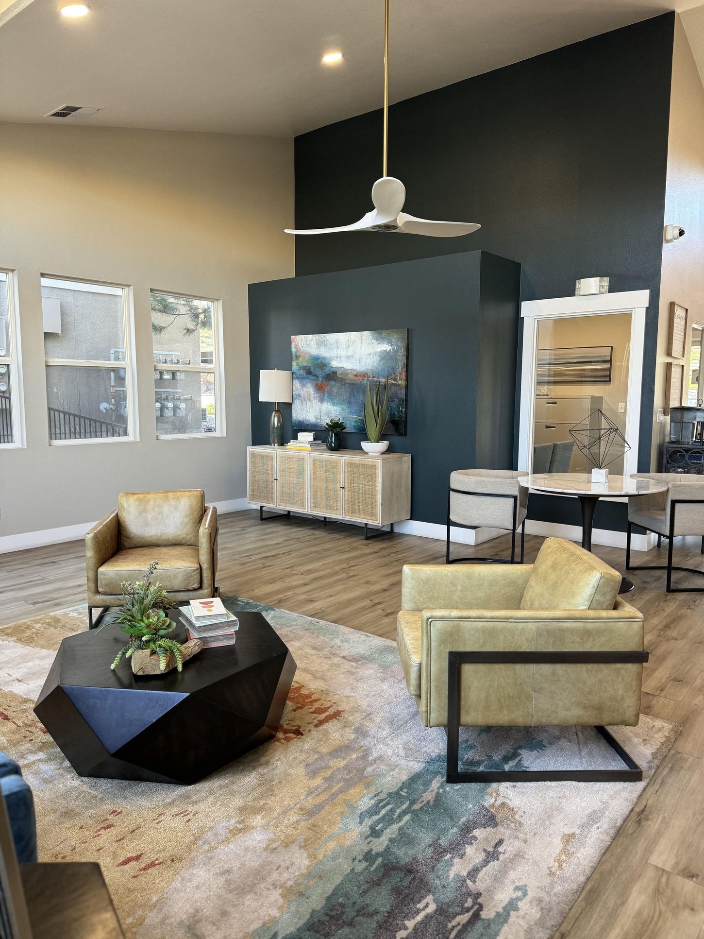 Lounge area with neutral walls, teal accent wall, modern furniture, area rug, and a ceiling fan.