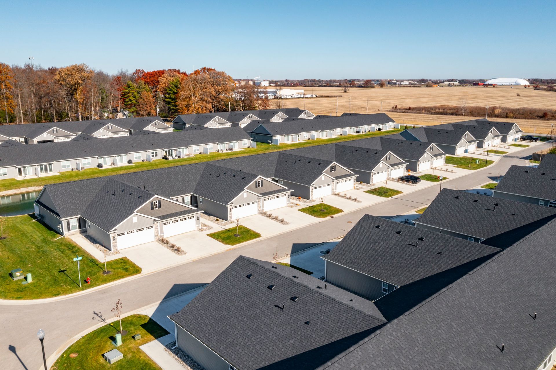 Photo of a few rows of duplexes with trees and fields in the background