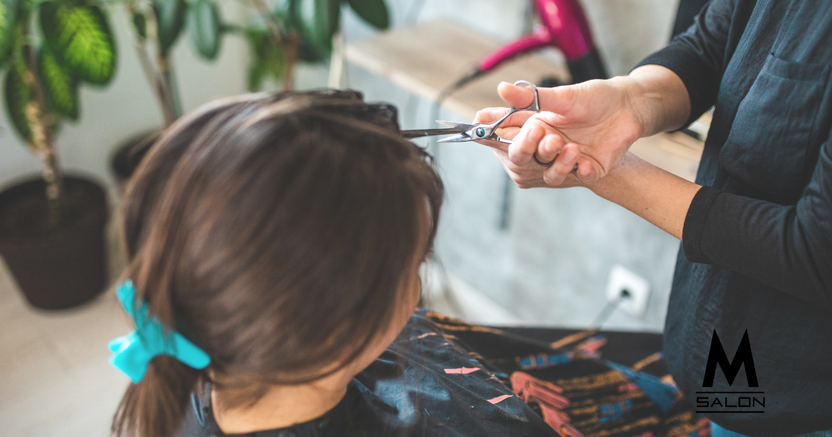 A woman is getting her hair cut by a hairdresser.