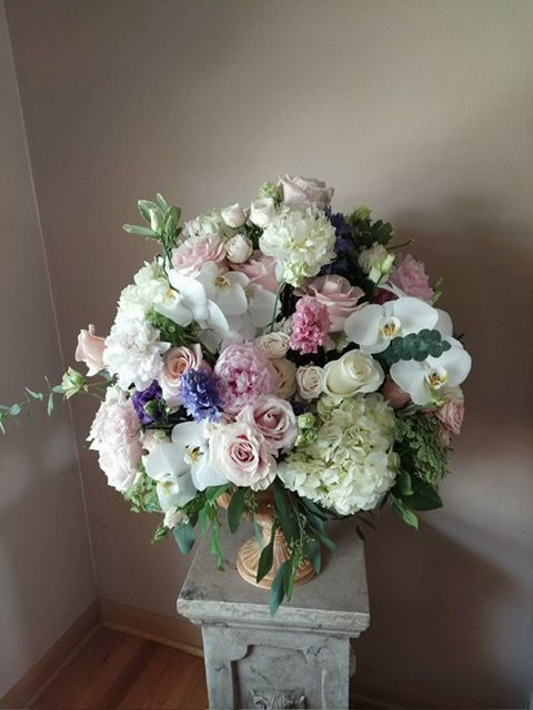 A vase filled with flowers is sitting on a pedestal.