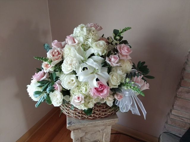 A basket filled with white and pink flowers is sitting on a pedestal.