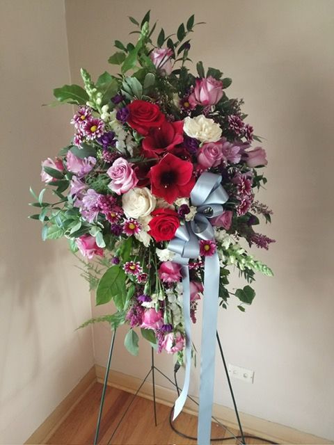 A display of flowers on a stand with a blue ribbon