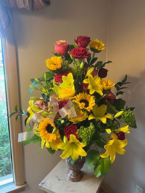 A vase filled with flowers is sitting on a table in front of a window.