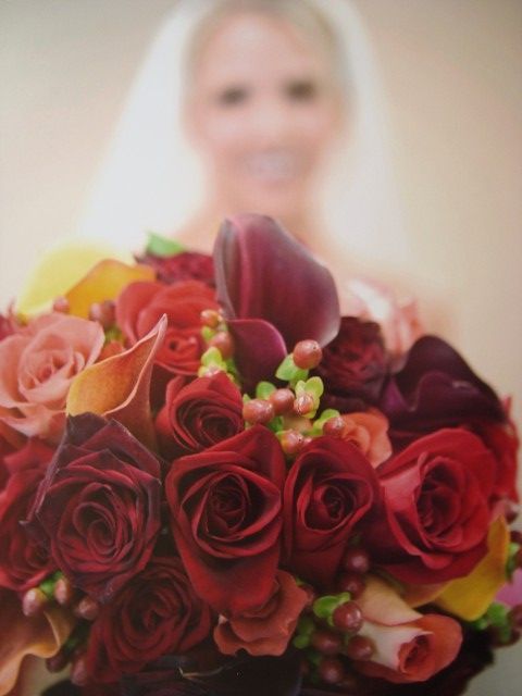 A blurry picture of a bride holding a bouquet of red roses