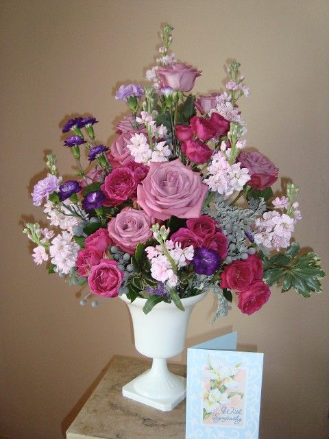 A vase filled with pink and purple flowers next to a card