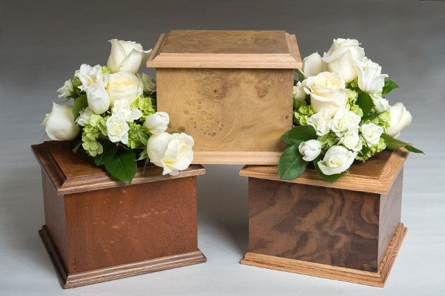 Three wooden urns with flowers in them on a table.