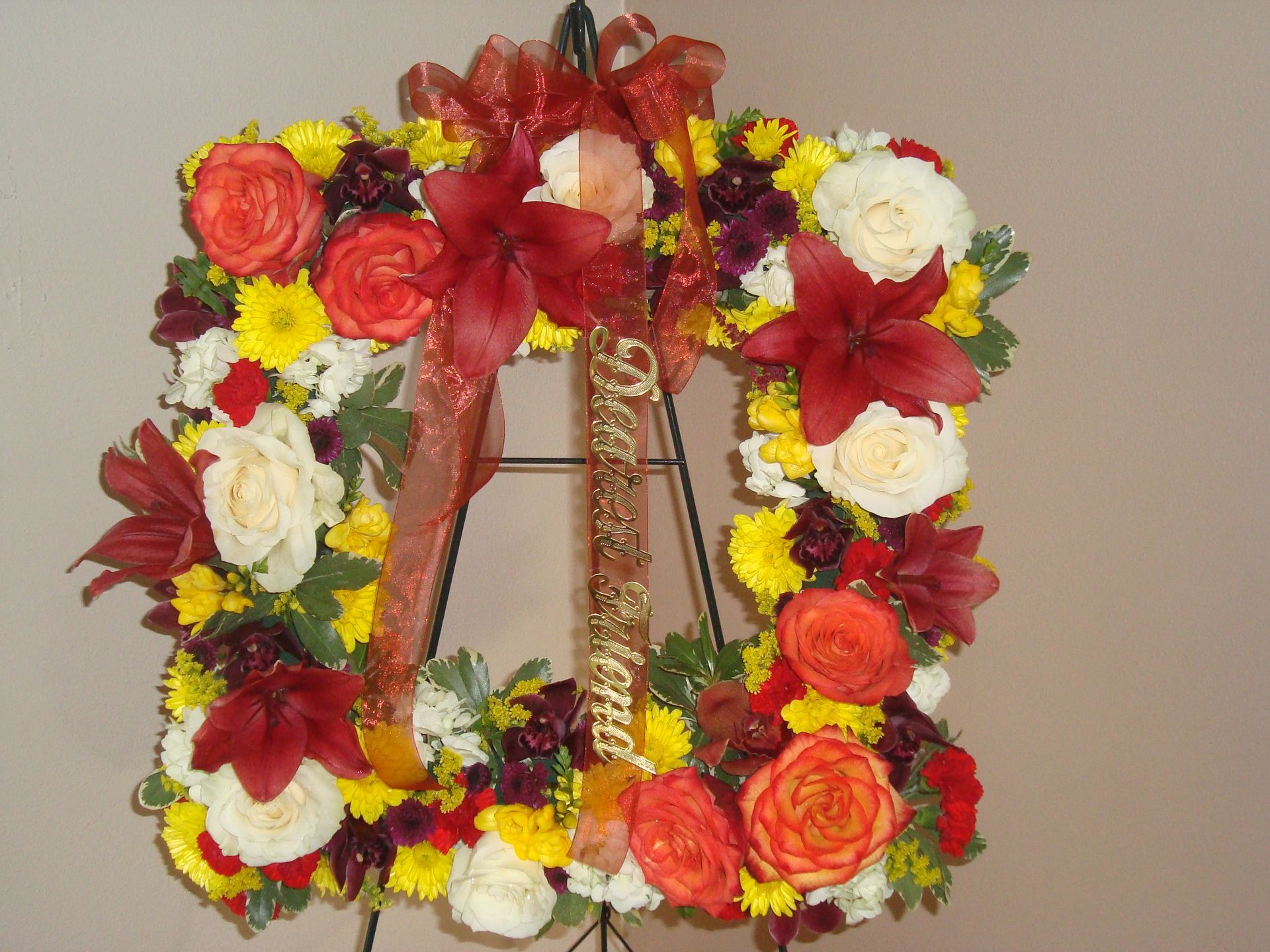 A wreath of flowers with a red ribbon that says merry christmas