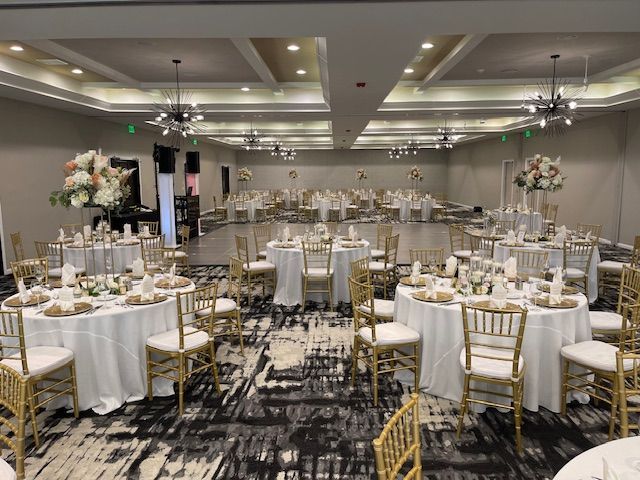 A large room with tables and chairs set up for a wedding reception.