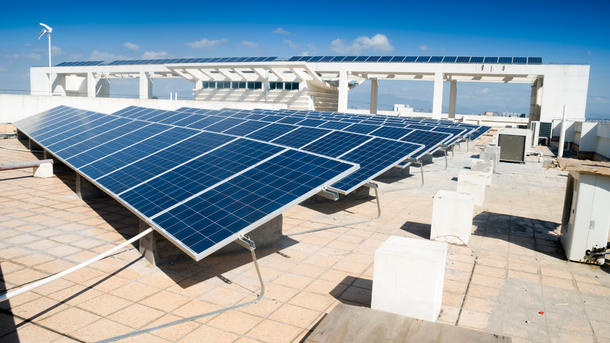 There are many solar panels on the roof of a building.